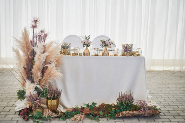 Wedding decoration in boho style.Light colors, in the tent.Wedding table decorated with pampas grass. Roses and gold geometric candlesticks