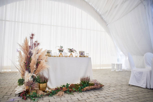 istock Wedding decoration in boho style.Light colors, in the tent.Wedding table decorated with pampas grass. Roses and gold geometric candlesticks 1172423232