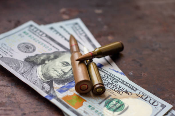 미국 달러 배경에 다양한 무기 총알. 군사 산업, 전쟁, 글로벌 무기 무역 및 범죄 개념. - currency crime gun conflict 뉴스 사진 이미지
