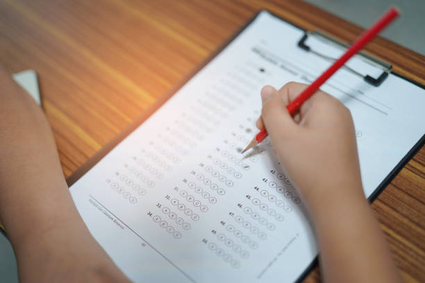 istock Asian children young kid write answer in a quiz examination test study learn on wooden table in school : bright genius education concept. 1172424306