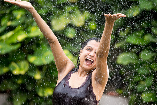 Excited young woman enjoying rain