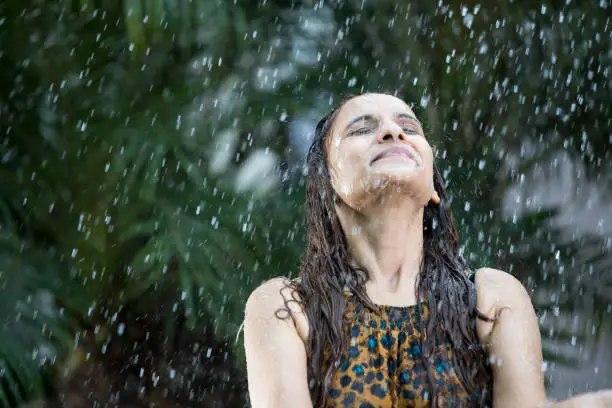 Excited young woman enjoying rain