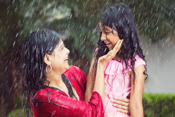 Drenched mother and daughter having fun on a rainy day
