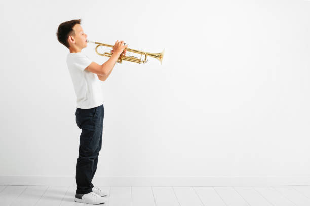 istock a child playing trumpet on turquoise background 1172428557