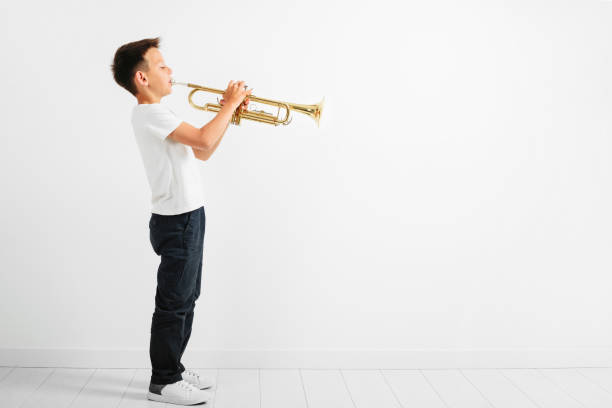 a child playing trumpet on turquoise background stock photo
