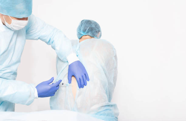 un anestesiólogo masculino realiza un procedimiento quirúrgico que introduce anestesia epidural en la parte posterior de una niña durante el parto, médico, - sensibility fotografías e imágenes de stock