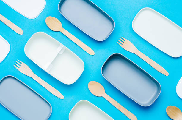 Pattern of plastic empty two-layered lunch boxes with wooden forks and spoons Pattern of plastic empty two-layered lunch boxes with wooden forks and spoons on blue background. Top view, flat lay. empty bento box stock pictures, royalty-free photos & images