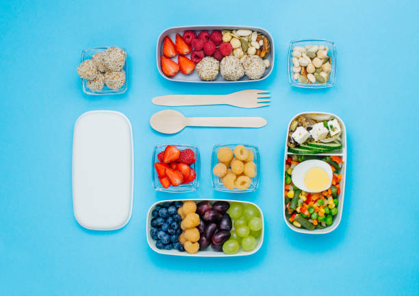 muster aus plastik-lunchboxen gefüllt mit gesunden lebensmitteln, frischem obst und beeren auf blauem hintergrund - bento box lunch healthy lifestyle stock-fotos und bilder