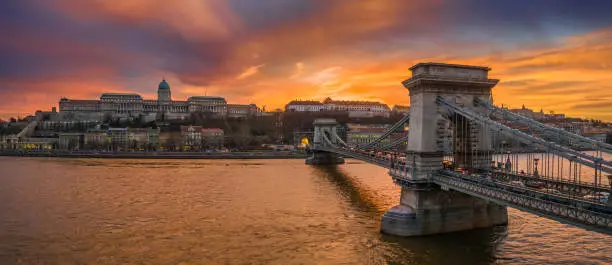 Budapest, Hungary - Aerial panoramic view of Szechenyi Chain Bridge with Buda Tunnel and Buda Castle Royal Palace at background with a dramatic colorful sunset