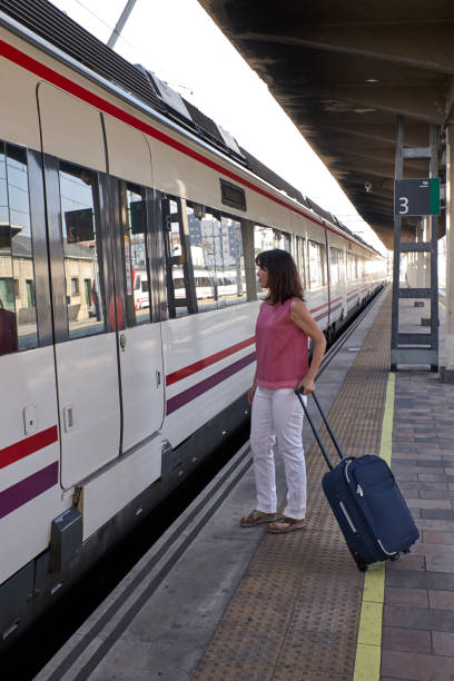 istock woman waiting for the train with a suitcase 1172438646