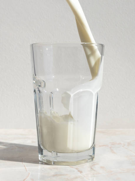istock Fresh milk pouring into a glass staying on light marble table 1172439816