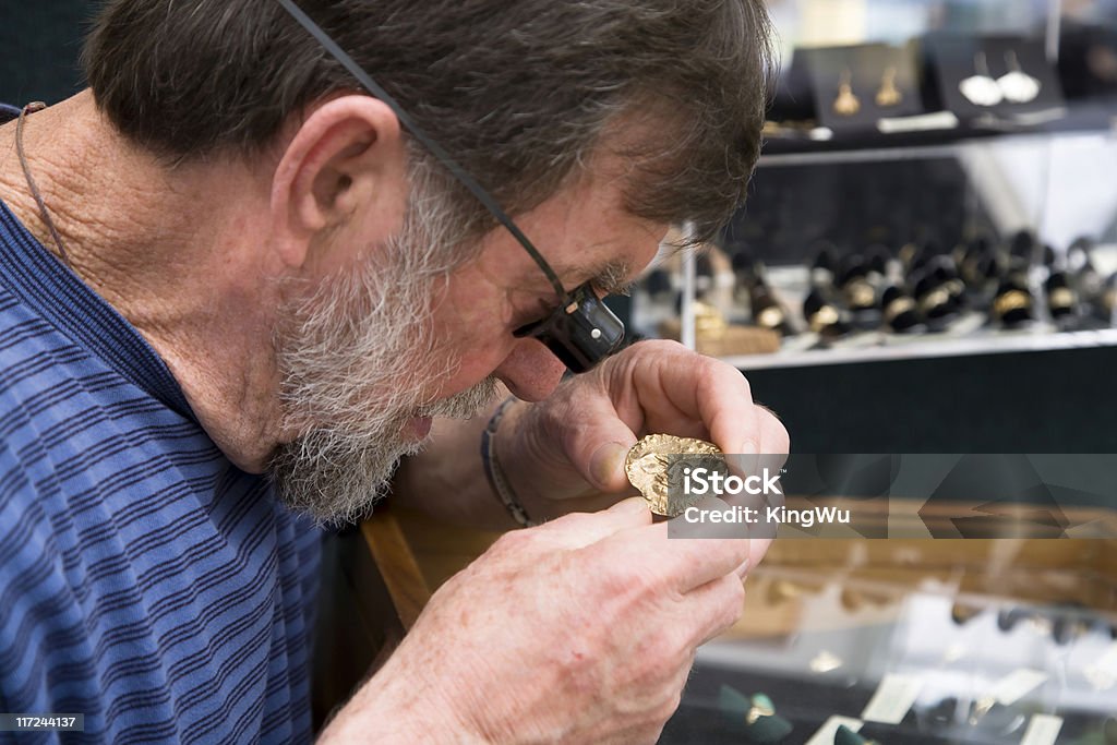 The Appraiser Jeweller using an eye loupe examining a pendant. Gold - Metal Stock Photo