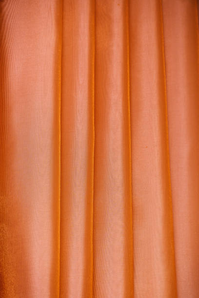 istock Vertical folds on orange organza curtains 1172443862