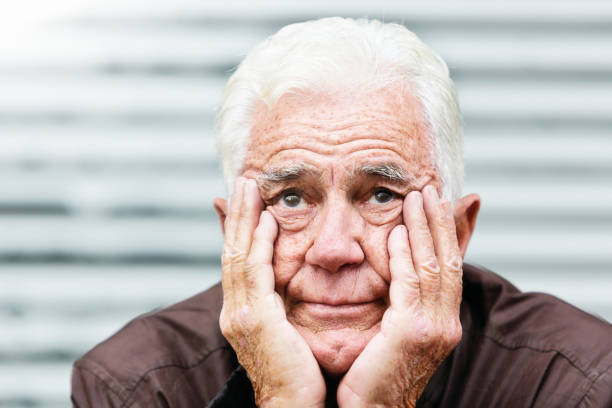 o homem idoso de desemparelhamento, cabeça nas mãos, olha a câmera - men mental illness loss despair - fotografias e filmes do acervo