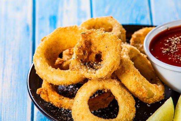 istock Onion rings with ketchup on wooden table 1172445819