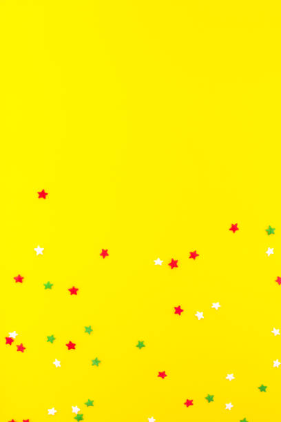 istock Multicolored festive stars sprinkles as a frame on yellow background. 1172446051