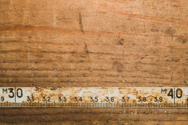 istock Old rusty ruler with black numbers on a working wooden table. vintage measuring tape. industrial background 1172452774