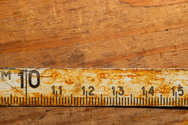istock Old rusty ruler with black numbers on a working wooden table. vintage measuring tape. industrial background 1172454190