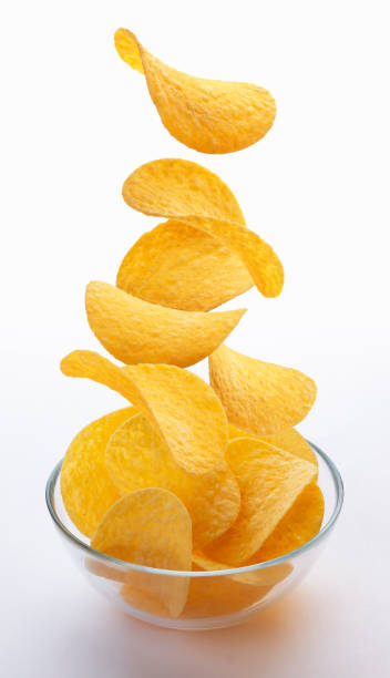 istock Potato chips falling into glass bowl isolated on white background 1172456230