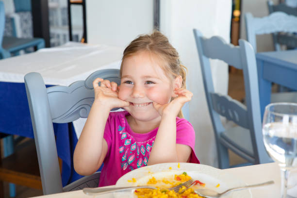 istock little girl making fun with paella dish in restaurant 1172468034