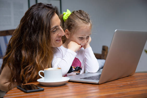 istock happy girl and mother smiling watching notebook computer 1172468089