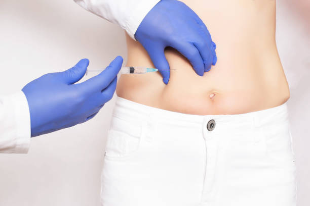 docteur cosmétologue fait des injections de botox et le rajeunissement dans l'estomac d'une fille. lissage des rides et des rides sur l'abdomen à l'aide d'injections de rajeunissement hyaluronique de l'acide, botulinum - bacille botulique photos et images de collection