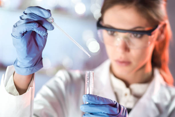 joven científico pipeteando en el laboratorio de ciencias de la vida. - scientist chemist doctor lab coat fotografías e imágenes de stock