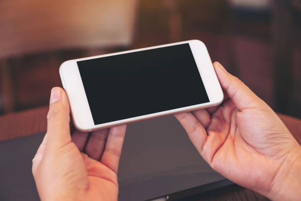 istock woman's hands holding black mobile phone with blank white screen 1172484320