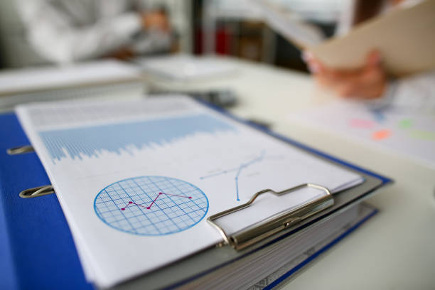 Business chart lie on table against group people office background. Seminar financial statistic analisys concept. Class room education lesson