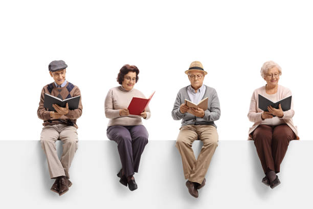 istock Group of elderly people sitting on a white panel reading books 1172488206