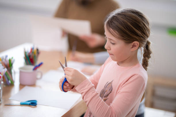 istock Girl cutting paper in classroom 1172490551