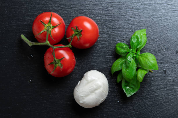 tomates, mozzarella et basilic sur une assiette d'ardoise - mozzarella caprese salad tomato italian cuisine photos et images de collection