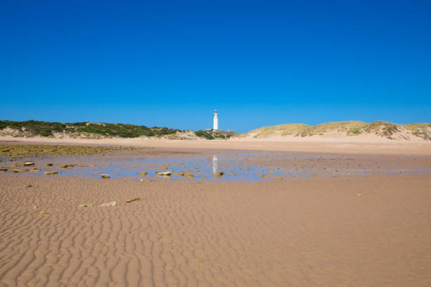 istock lighthouse of Trafalgar Cape reflected in water on sand beach 1172495426