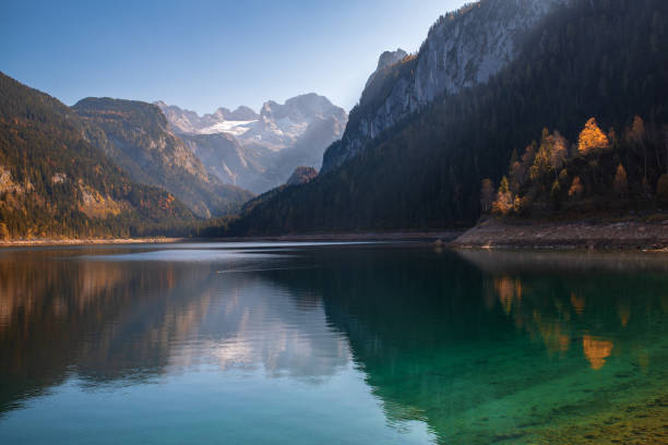 Autumn scenery of Gosausee lake with mountains reflected in the surface water and Dachstein mountain summit (World UNESCO heritage site) on background, Salzkammergut region, Upper Austria