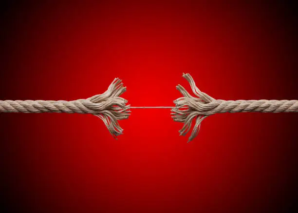 Frayed rope about to break on red background.