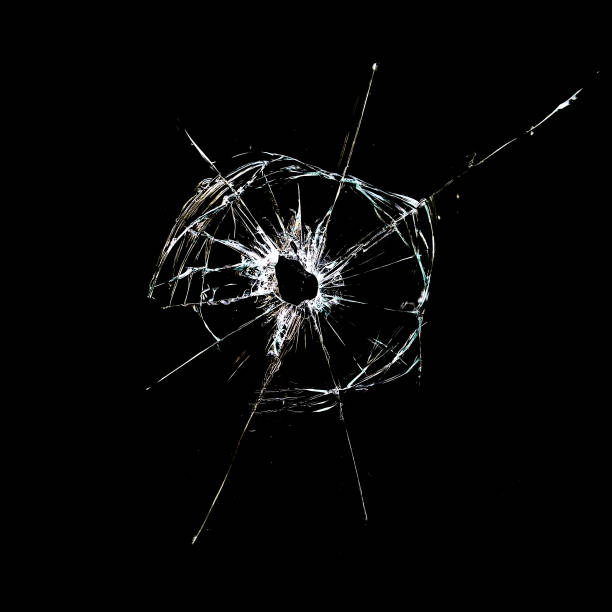 trou avec des fissures dans le verre isolé sur un noir - bullet hole glass window broken photos et images de collection