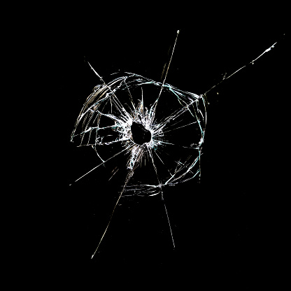 hole with cracks in the glass isolated on a black background