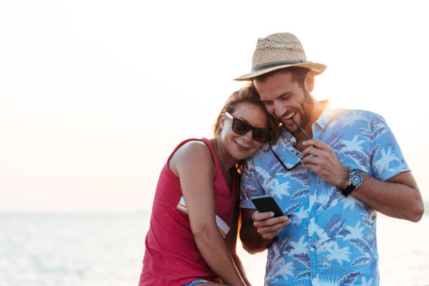 istock Young happy couple using smartphone by the sea 1172508172