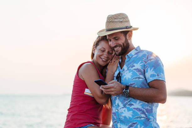 istock Young happy couple using smartphone by the sea 1172508175