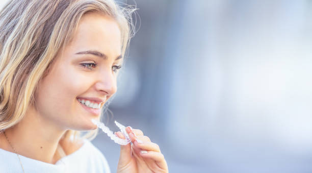 Invisalign orthodontics concept - Young attractive woman holding - using invisible braces or trainer. stock photo