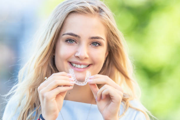 Invisalign orthodontics concept - Young attractive woman holding - using invisible braces or trainer. Invisalign orthodontics concept - Young attractive woman holding - using invisible braces or trainer. dental aligner photos stock pictures, royalty-free photos & images