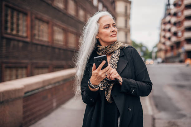 istock Beautiful senior lady using mobile on the street 1172510990