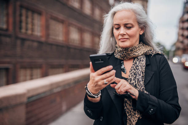 istock Beautiful mature lady using mobile on the street 1172511024