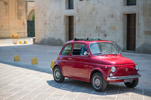 Melpignano, Italy - A red classic Fiat 500 car parked in the street