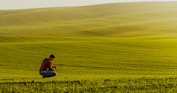 Man squatting on green meadow, Moravian Slovakia,Czech Republic