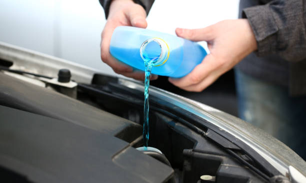 Male serviceman hands pouring blue washer Male serviceman hands pouring blue washer fluid from a bottle into car concept coolant stock pictures, royalty-free photos & images