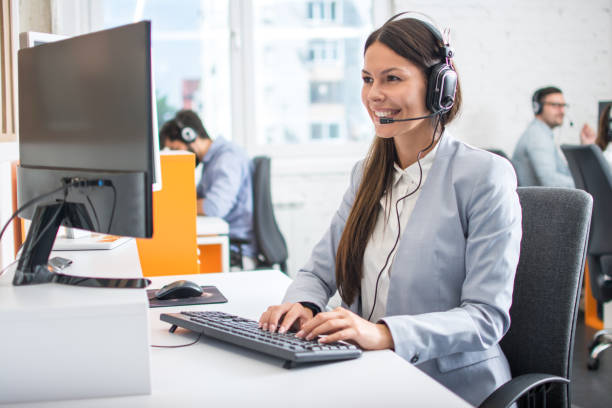 istock Female professional call center telesales agent wear wireless headset using computer in customer care support service office with team. 1172520571