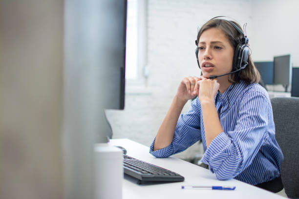 istock Beautiful young call centre telephone worker talking with a client while sitting bellow computer. Copy space on left side. 1172520951