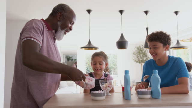 Grandfather Serving Ice Cream To Grandchildren In Kitchen