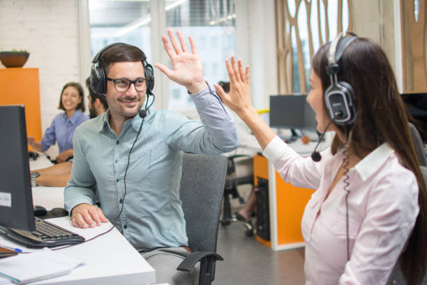 Customer service support operators giving high five to each other and celebrating successful completed task